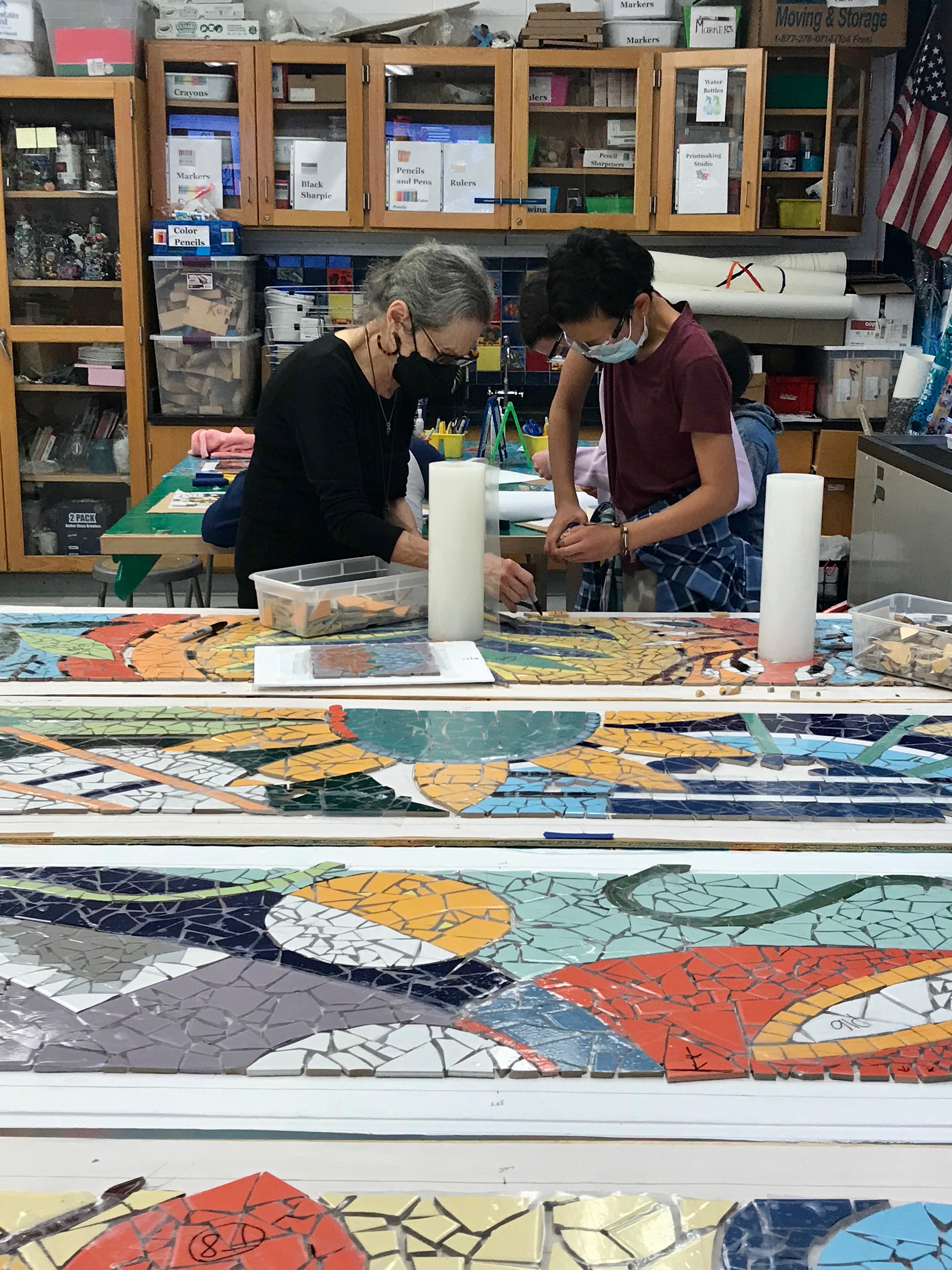 Mirtes working with student on mosaic mural