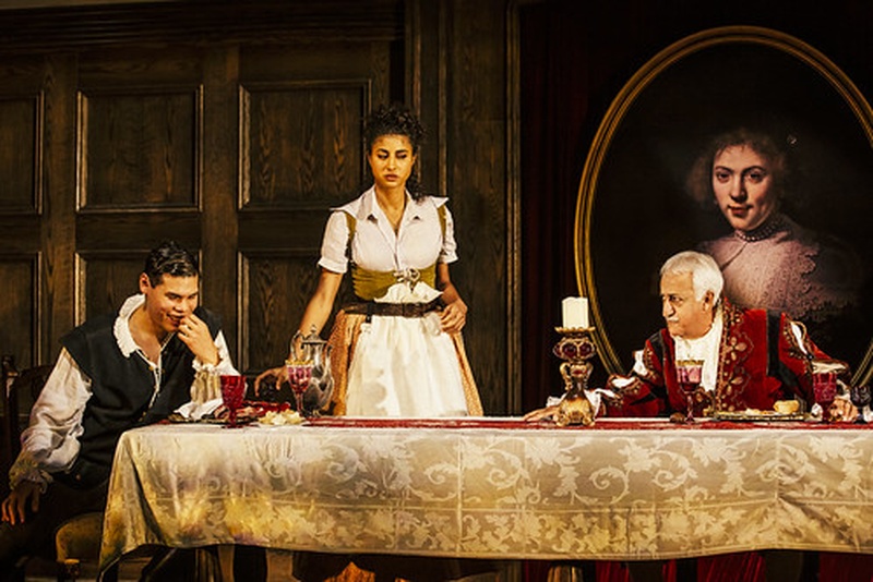  Vella Lovell, Brian George, and Ruy Iskandar in Witch by Jen Silverman directed by Marti Lyons at the Geffen Playhouse, 2019, Brian and Ruy around a banquet table, Vella stands with dishes between them 