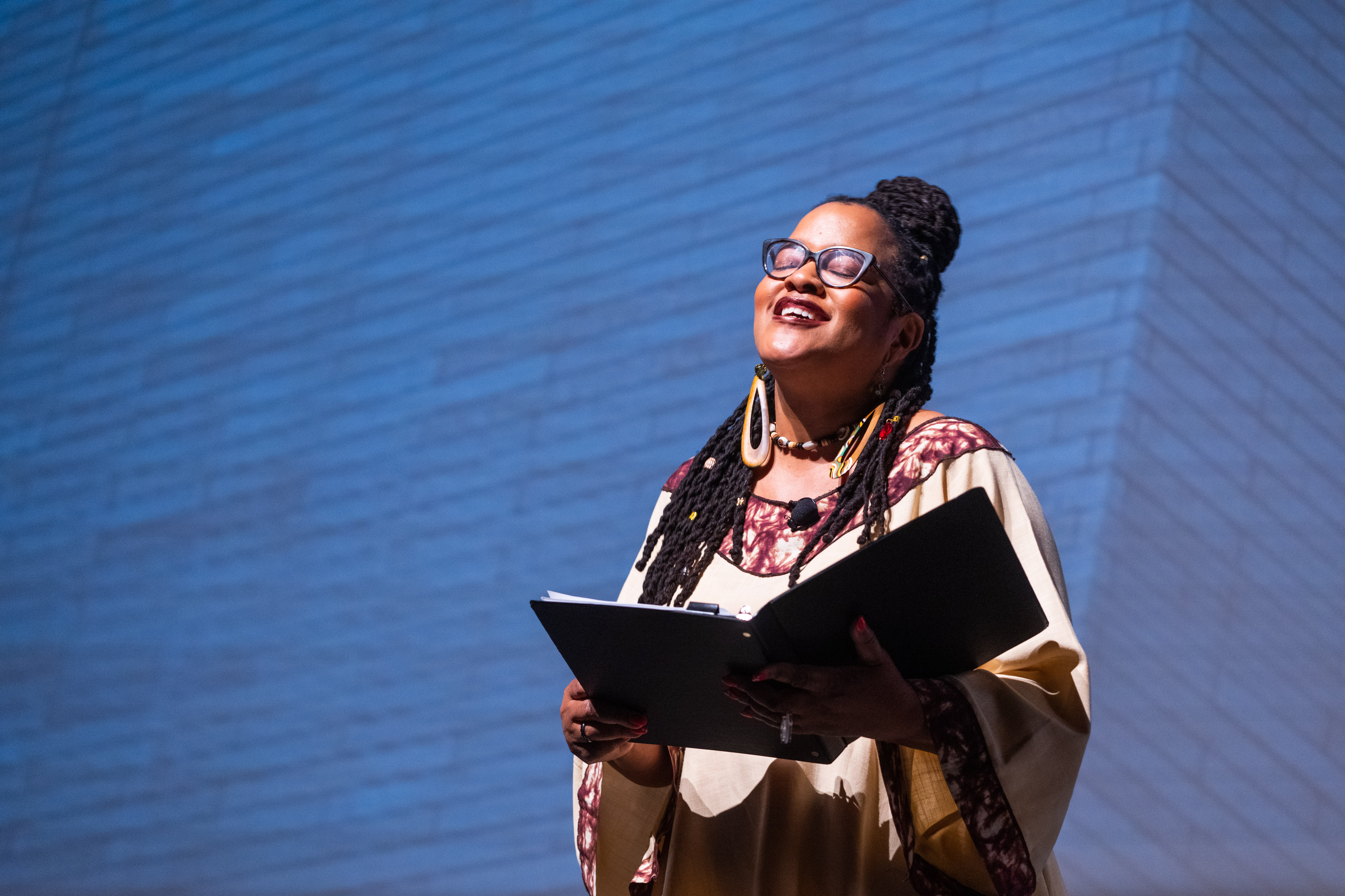 Black woman with long hair holing book against a blue background