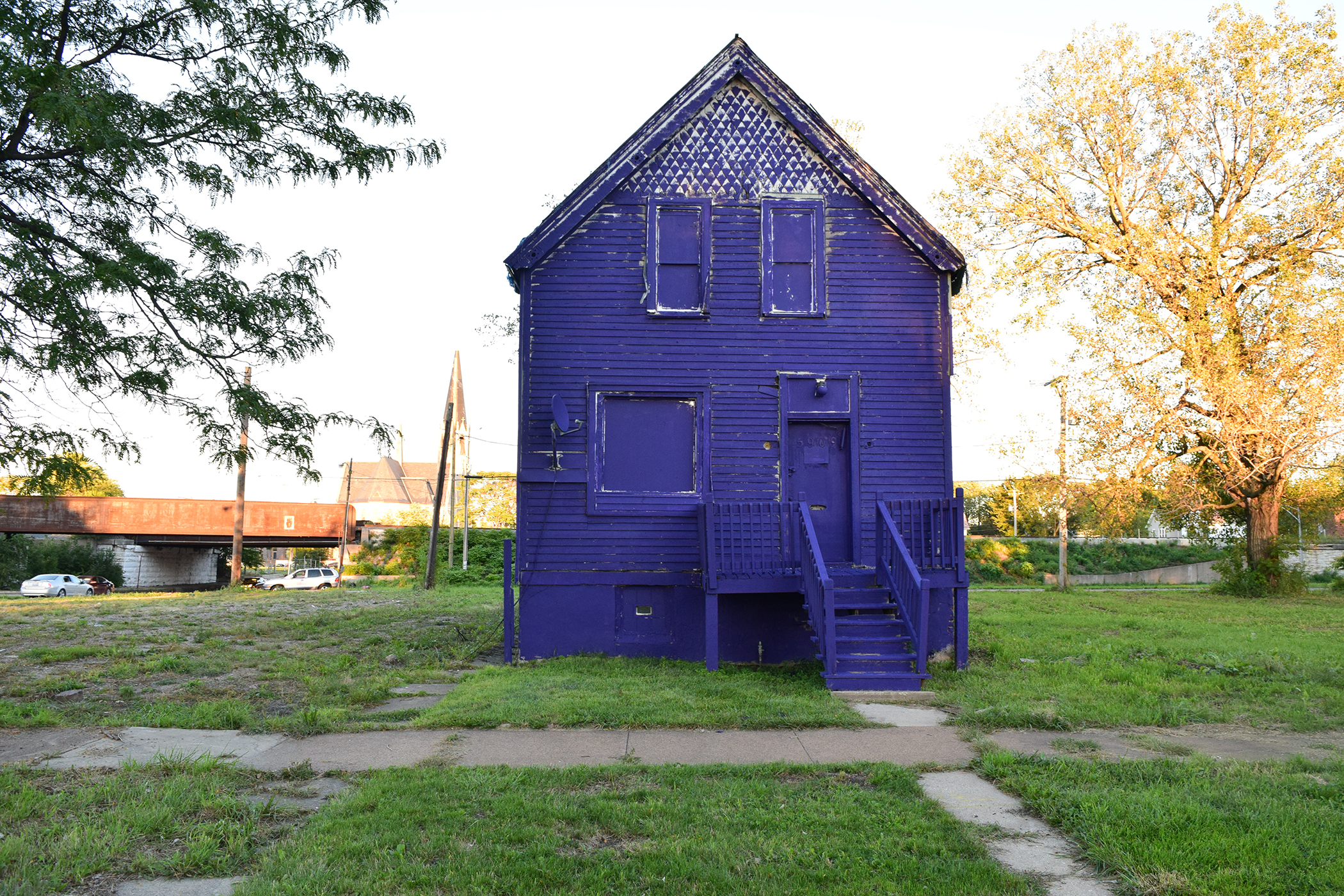 worker housing with gabled roof painted purple sitting in an isolated field