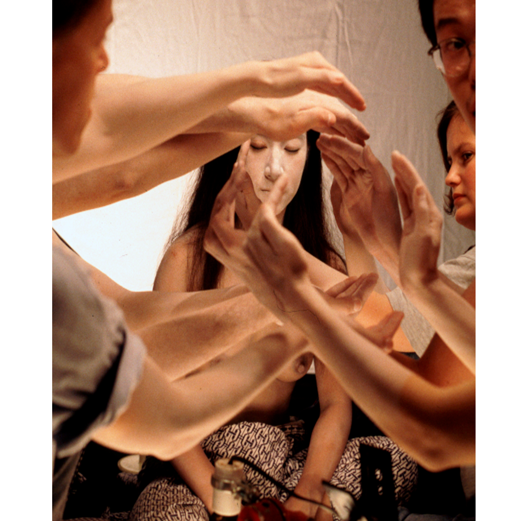 A group of dancers with arms forming a lens shape infront of a woman's face.