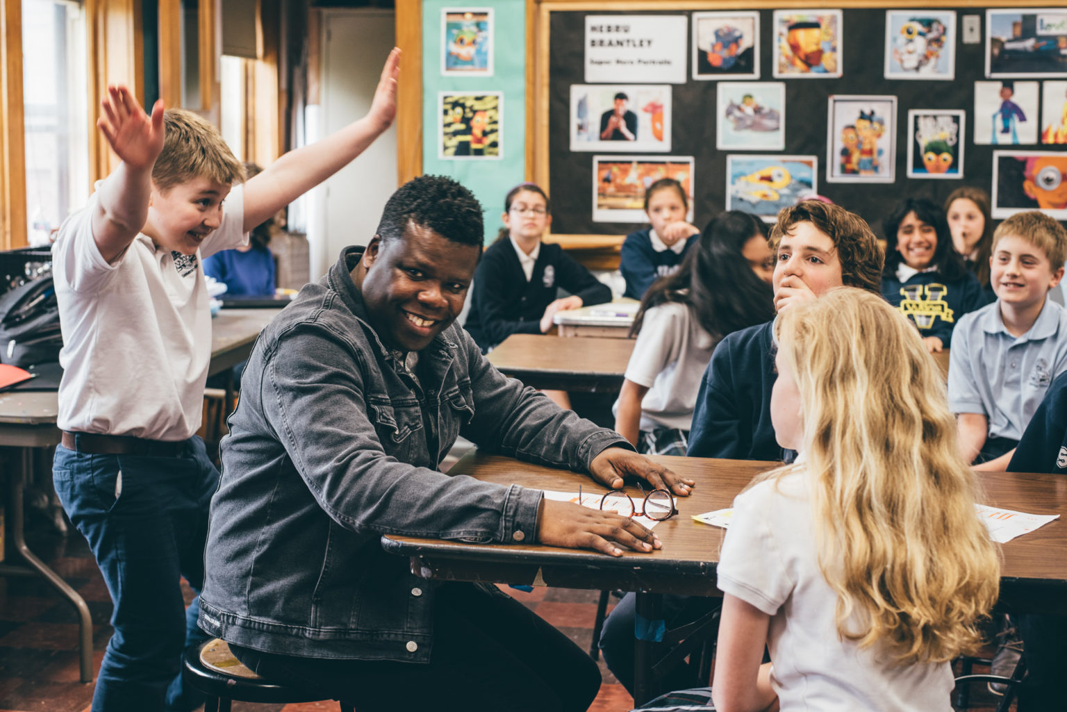 african -american teaching artist smiling in a classroom of diverse students