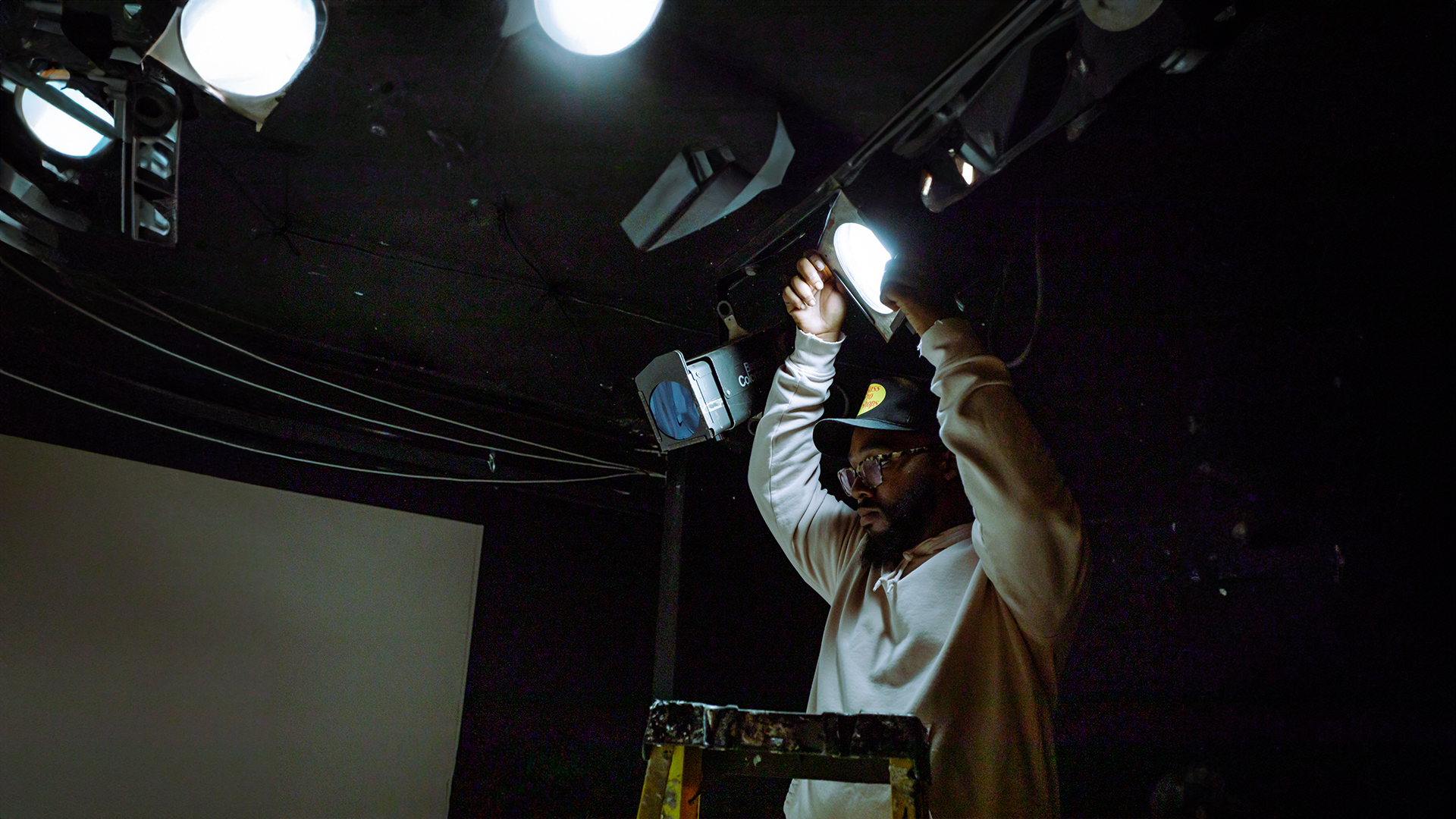 person stands on letter and adjusts stage light