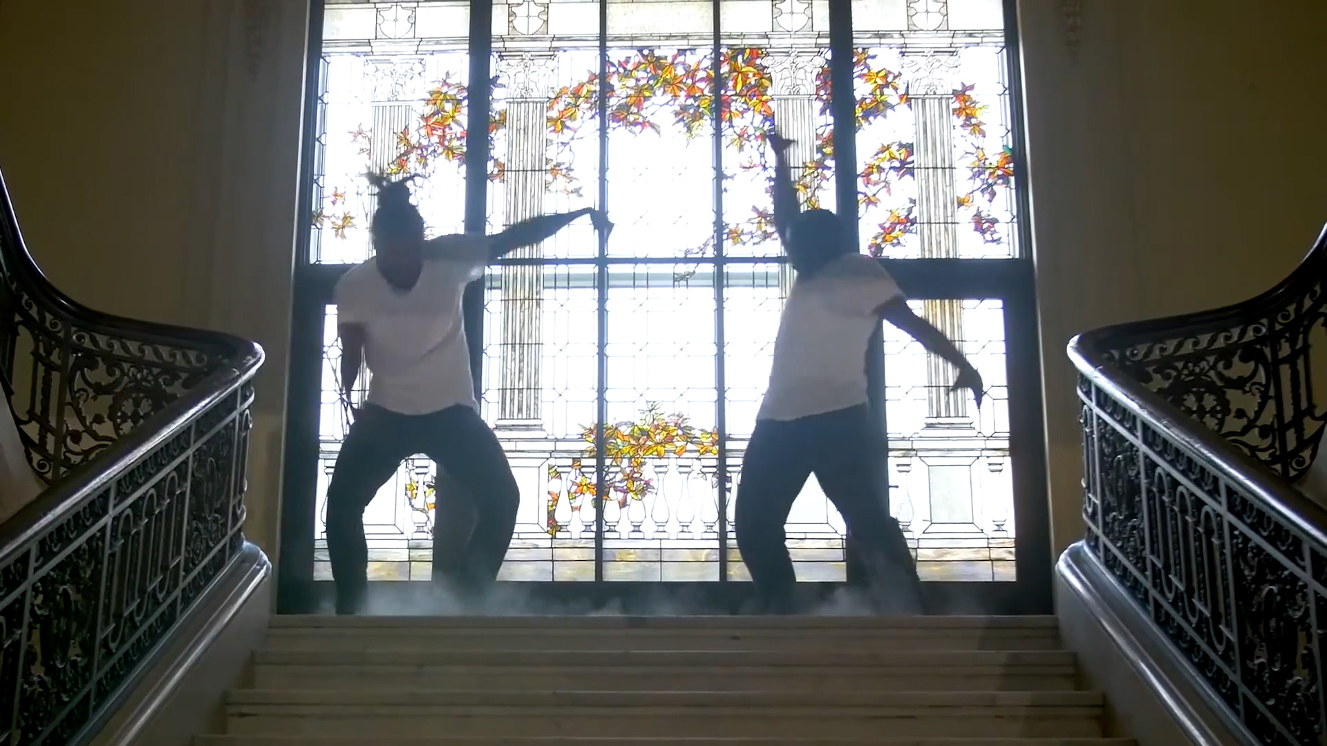 two men dancing in front of a stainglass window