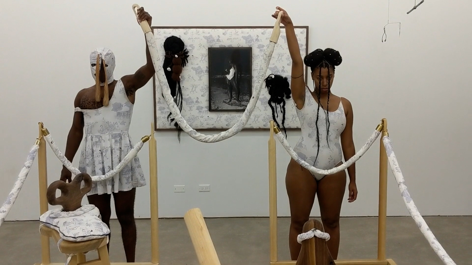 Two figures in an installation/performance holding up a rope