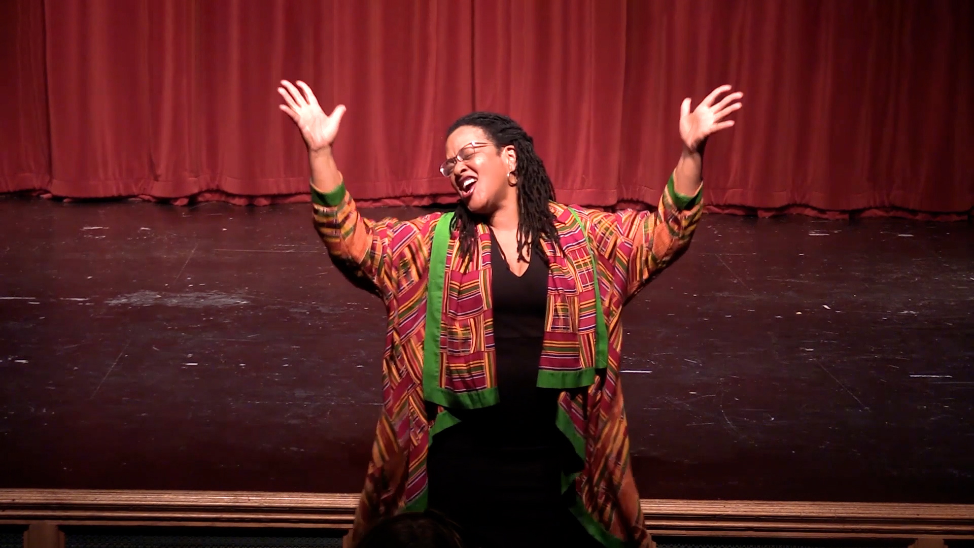 Emily Hooper Lansana with her arms extended in front of a stage