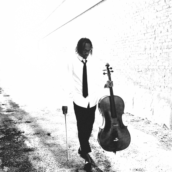  Artful portrait of a Black man with locs wearing a white shirt and tie, striding slowly while holding a cello in one hand and a bow in another 