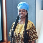 black Woman smiles at the camera and is wearing blue turban