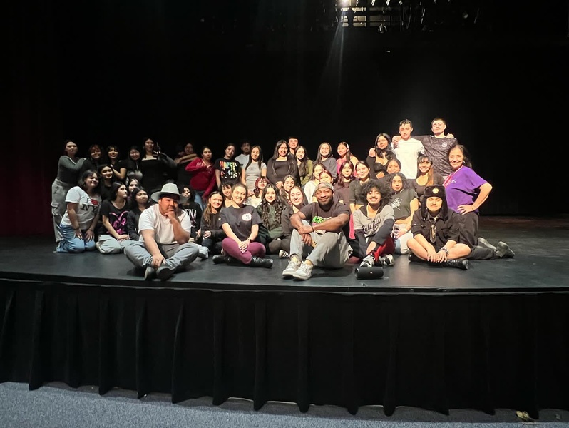  group of people sit on black stage and smile at camera 