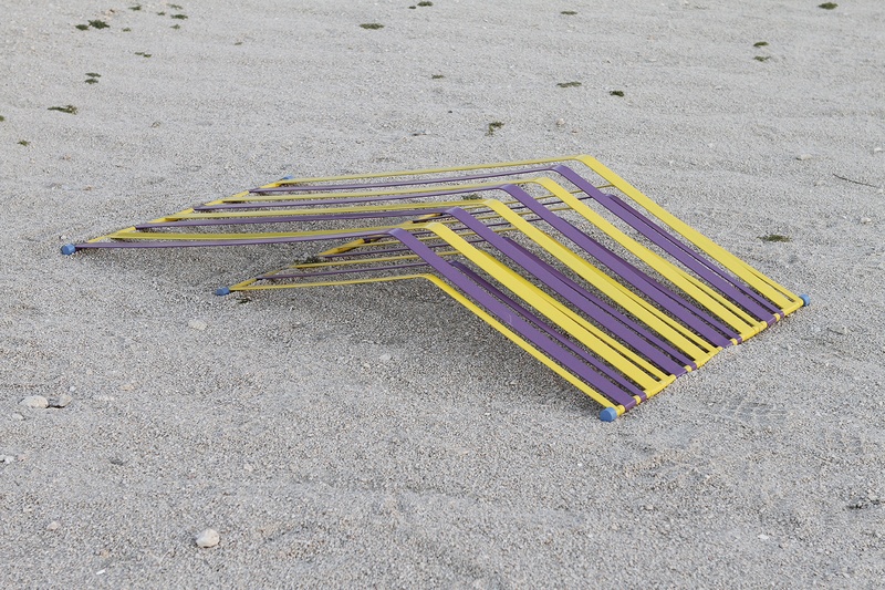  A geometric sculpture peaks out of sand and mimic beach chairs without legs 