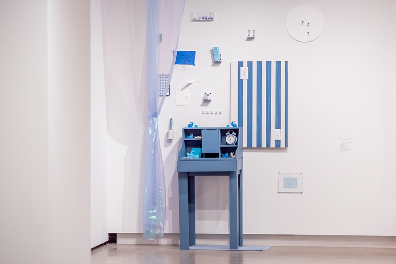  A collection of blue objects: A desk, portion of a wall, dart board. 