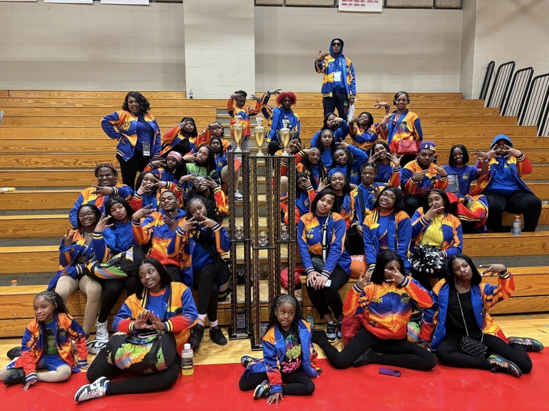  image of black children in orange and blue coasts sitting around first place trophy 