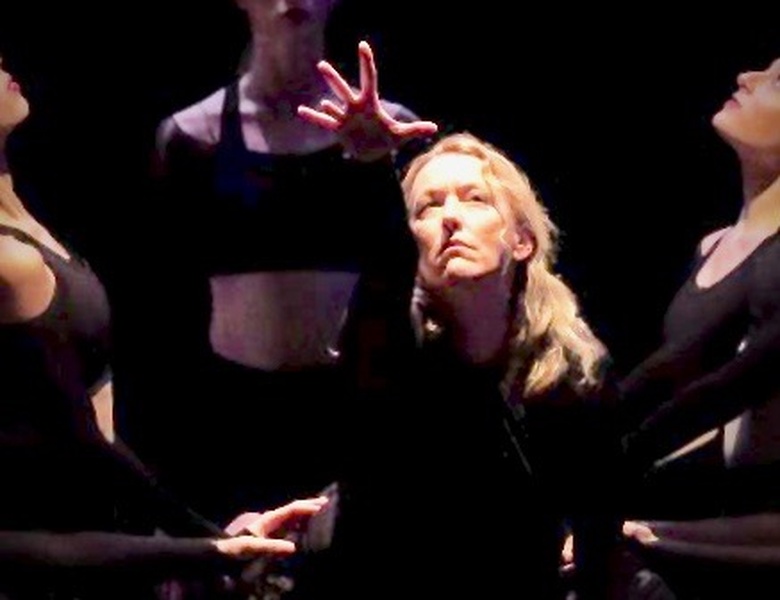  Ladonna reaching one arm while surrounded by dancers, all wearing black 