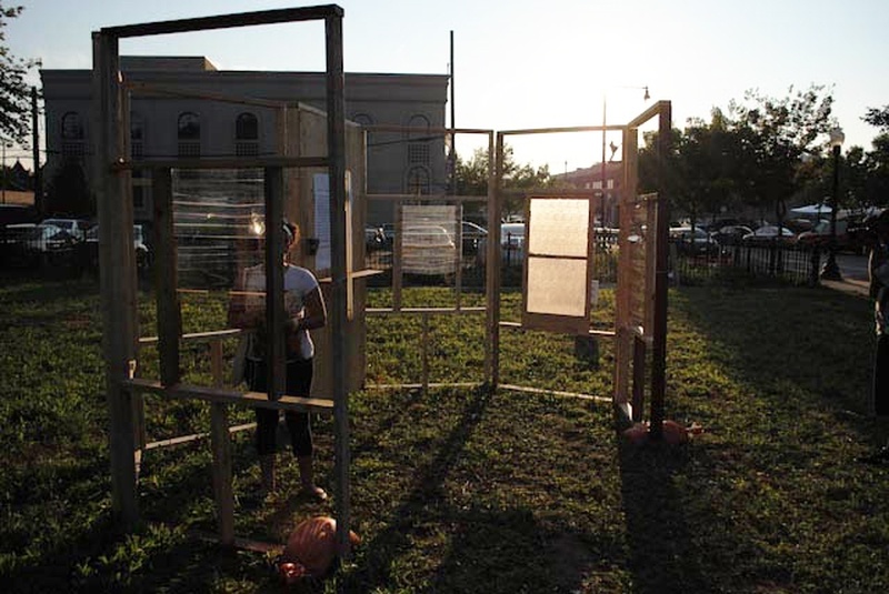  Person surrounded by wooden structure hangs window like panes 