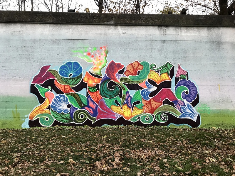  Graffiti painted on a wall with shapes that form waves, shells, and flowers. 