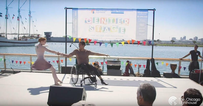  two dancers on stage in front of large body of water 