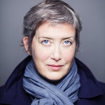 White woman with straight, short grey hair and blue eyes