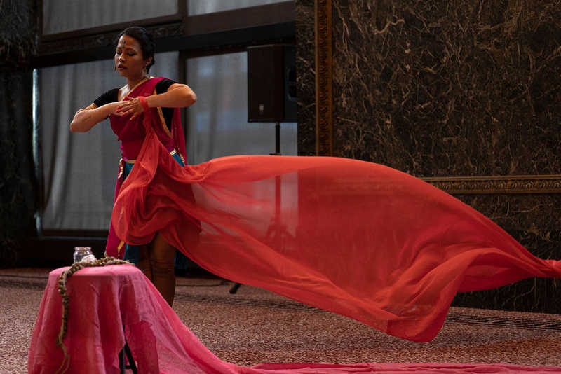  woman wearing red sari dances as sari catches wind and floats slowly to ground 