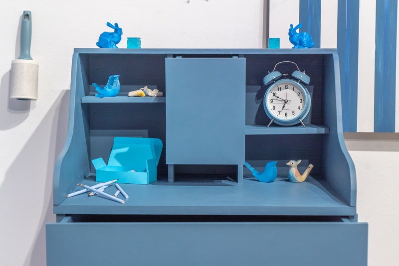  A close-up of a blue desk, two blue Stanford bunnies of different resolutions, alarm clock, bird whistles, a box of erasers, and broken pencils 