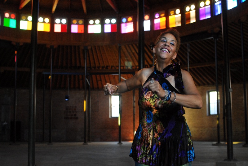  Woman smiles and dances in an empty room with color windows surrounding her on the ceiling. 