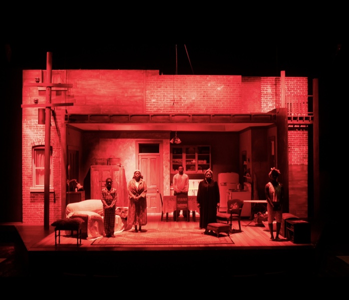  actors stand on stage under red light 