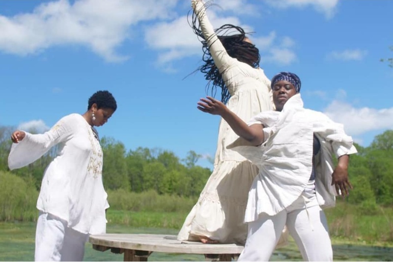  Three women dressed in white dance outside against a blue sky 