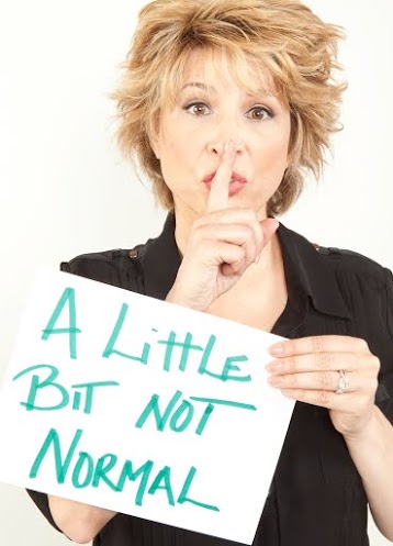Arlene with her finger over her lips, holding a sign that says A Little Bit Not Normal