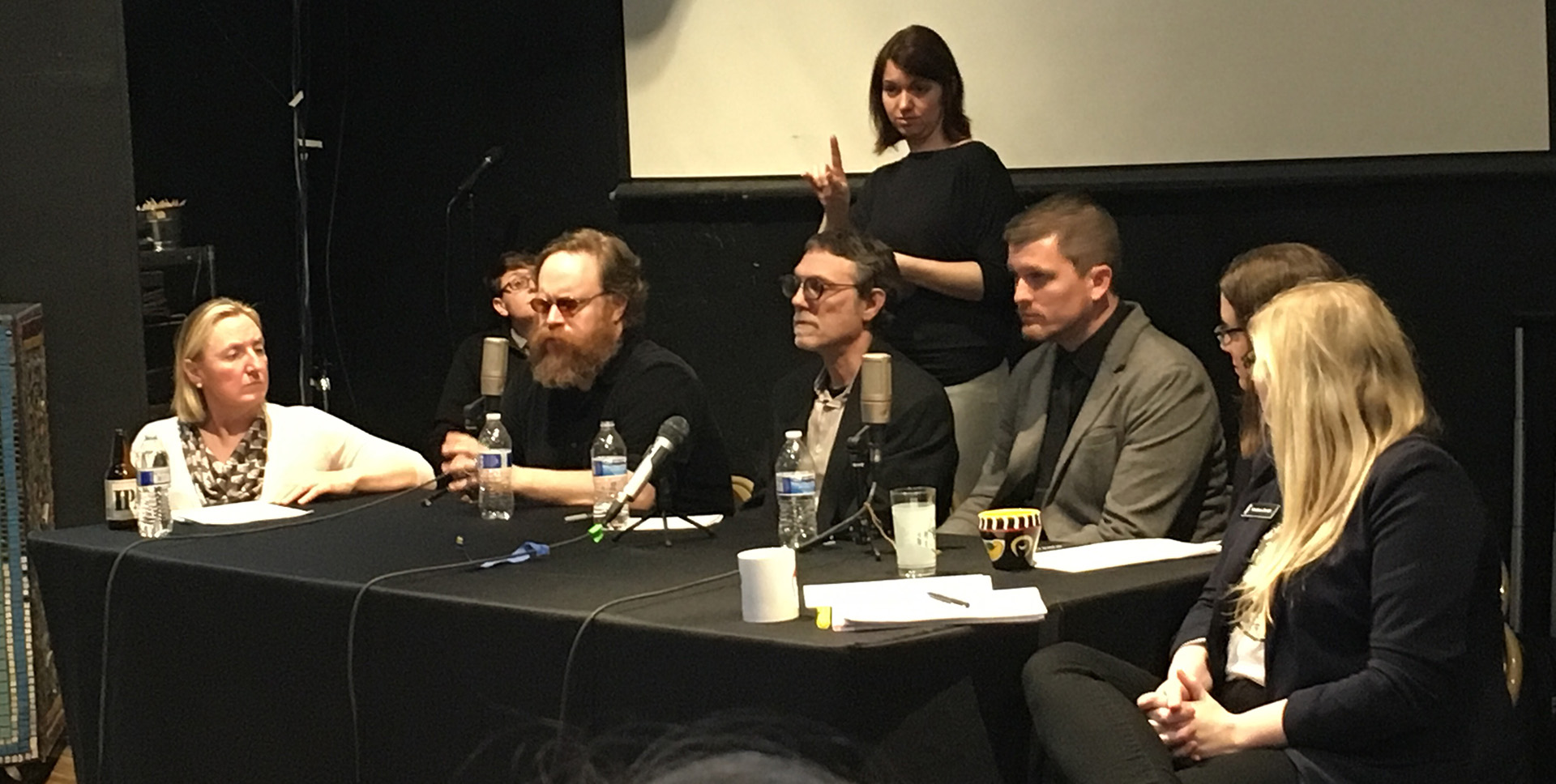 Artists at a panel discussion with an ASL interpreter behind them.