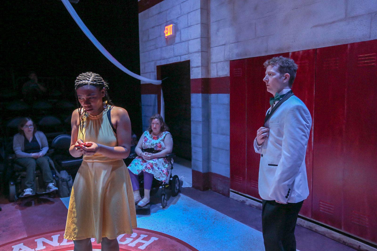 A Black girl and white boy look into the distance. A woman in a wheelchair is behind them.